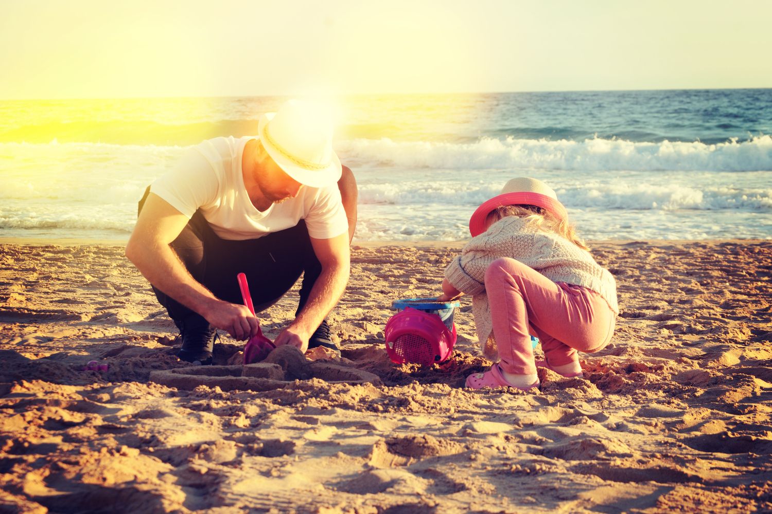 un père et sa fille faisant un château de sable